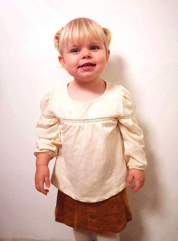 Amalia participe au concours pour gagner de l'argent avec cette photo : baby_toddler_clothing, cheek, child, day_dress, dress_shirt, elbow, embellishment, face, gesture, hair, happy, joy, neck, pattern, peach, person, sleeve, smile, sock, t_shirt