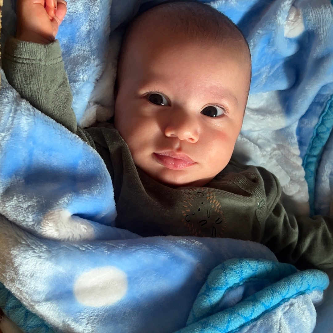 Noah a rejoint le concours — aidez-le/la à gagner de superbes lots ! baby, blanket, blue, child, clothing, curious, cute, expression, face, indoors, infant, lying_down, person, polka_dots, portrait, raised_fist, skin, soft_texture, warm, wrapped