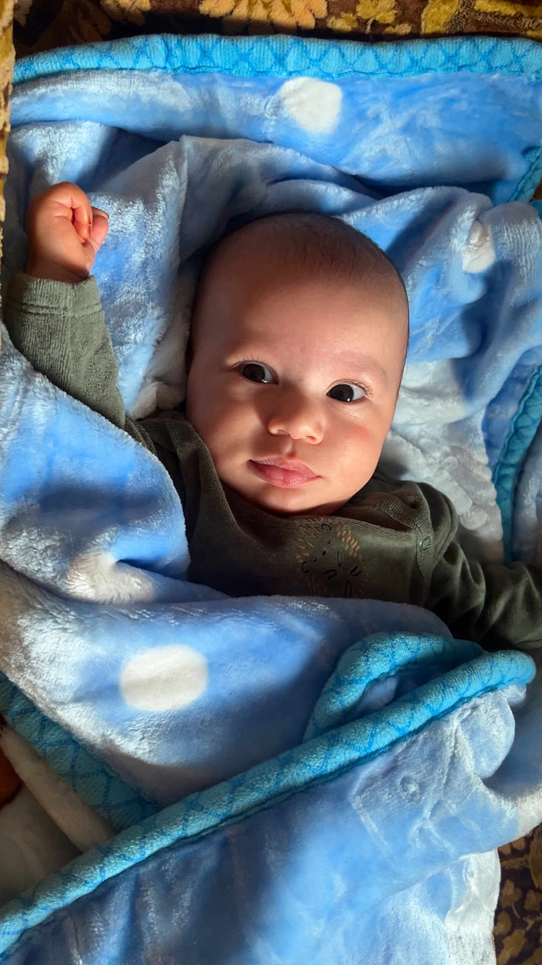 Noah a rejoint le concours — aidez-le/la à gagner de superbes lots ! baby, blanket, blue, polka_dots, face, infant, child, raised_fist, curious, cute, soft_texture, warm, wrapped, lying_down, indoors, portrait, skin, clothing, expression, person
