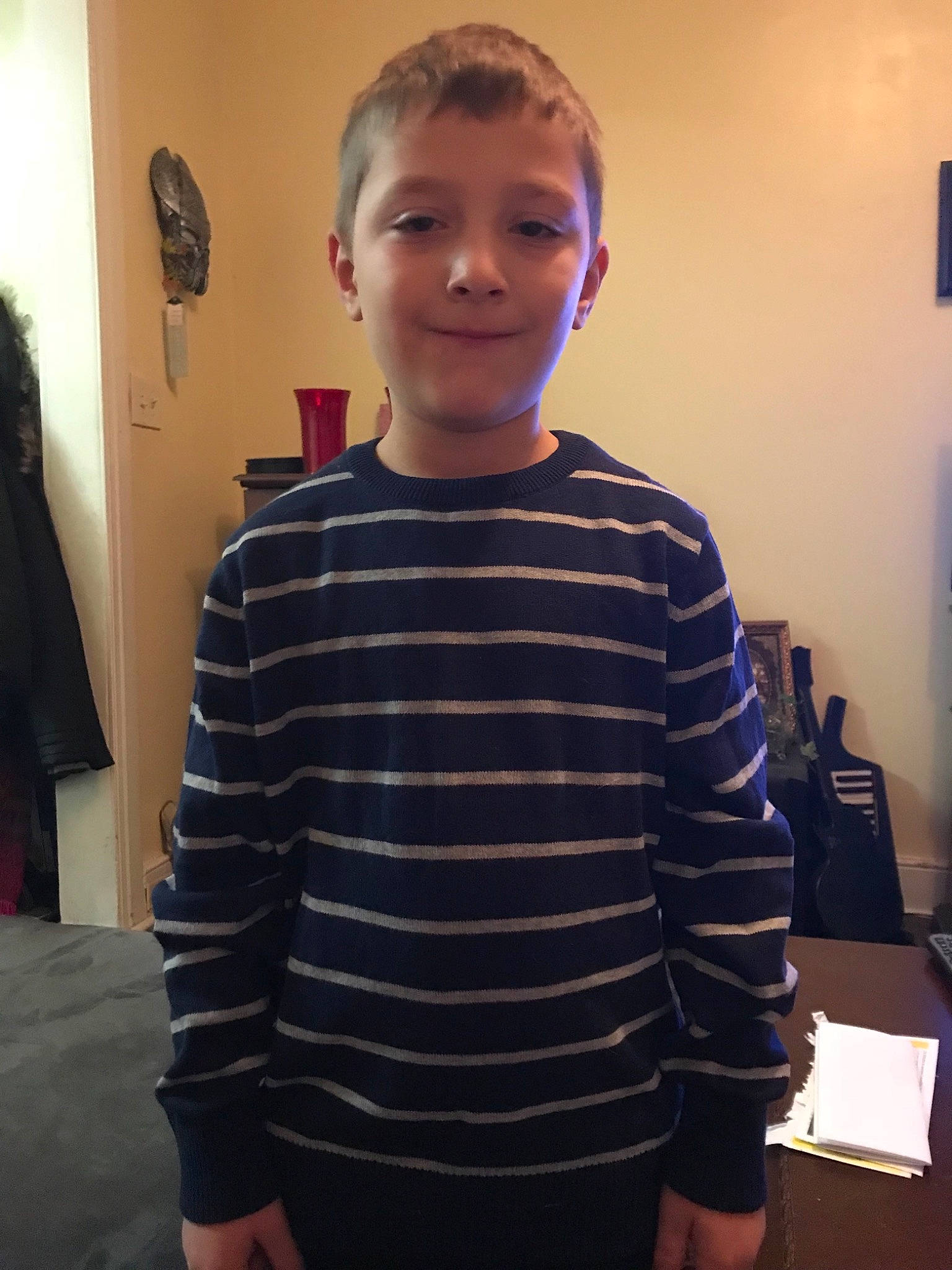 Nicholas is registered to the contest to win money with this photo: child, face, head, joint, neck, outerwear, person, room, shirt, shoulder, sleeve, smile, standing, sweater, t_shirt, top