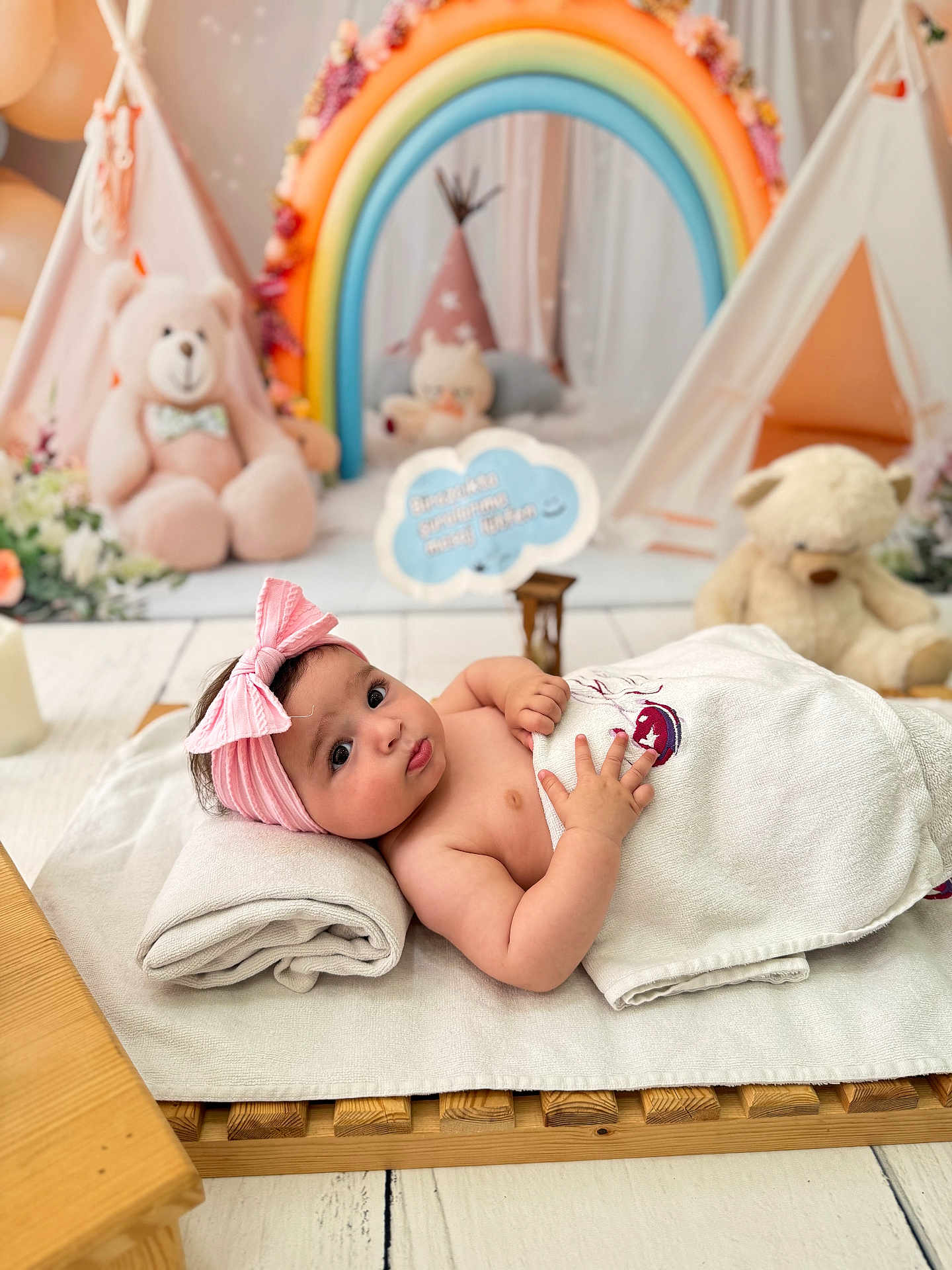 Diana is registered to the contest to win money with this photo: baby, infant, towel, pink_bow, headband, teddy_bear, rainbow, plush_toy, wooden_floor, blanket, cute, child, indoor, soft_lighting, portrait, laying_down, nursery, decor, toy, curious