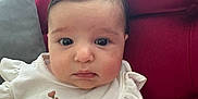 Diana joined the competition — help win amazing prizes! baby, infant, child, face, portrait, dress, floral, couch, red_couch, indoor, curtains, cute, sitting, person, young_child, fashion, plush, soft_lighting, home, adorable