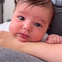 Diana is registered to the contest to win money with this photo: baby, infant, close_up, face, eyes, arm, skin, hair, person, portrait, resting, curious, indoors, soft_light, gray_shirt, blurred_background, child, cute, young, human