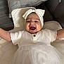 baby, child, smile, laughing, headband, white_dress, arms_outstretched, cushion, soft_surface, happy, infant, cute, indoor, portrait, toddler, headwear, button, fabric, clothing, person