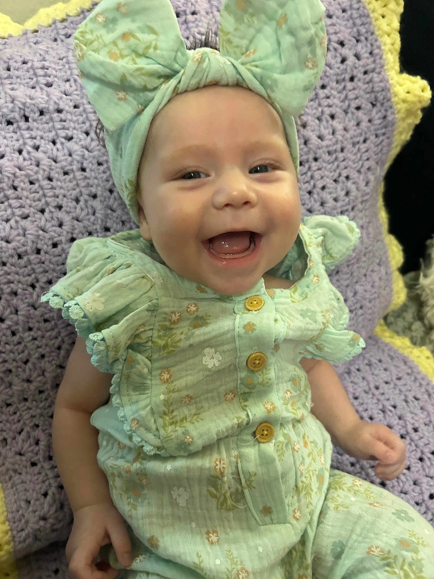 Novalee joined the competition — help win amazing prizes! baby, smile, headband, bow, mint_green, floral_pattern, outfit, crocheted_blanket, purple, yellow, happy, child, cute, infant, sitting, clothing, portrait, face, young_child, indoors