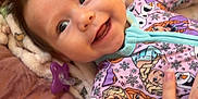 Novalee is registered to the contest to win money with this photo: baby, smile, child, infant, cushion, blanket, hand, clothing, pajamas, disney, frozen, portrait, happy, indoors, cute, young, person, face, closeup, soft