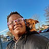 Véo a rejoint le concours — aidez-le/la à gagner de superbes lots ! brown_dog, car, casual, closeup, daytime, dog, glasses, happy, jacket, outdoor, parking_lot, person, portrait, puppy, shoulder, sky, smile, sunlight, trees, urban