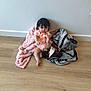 baby, child, blanket, floor, wood_floor, onesie, pacifier, indoor, curly_hair, caucasian, sitting, foot, cute, infant, wall, cozy, expression, pink, gray, soft_texture