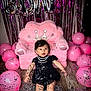 Princess Octavia is registered to the contest to win money with this photo: baby, black_dress, pink_balloons, confetti, plush_chair, princess_crown, birthday_balloons, purple_streamers, floor, celebration, party, infant, smiling, happy, indoors, cute, child, festive, decorations, event