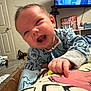 Easton Williams is registered to the contest to win money with this photo: baby, infant, smiling, blue_clothing, blanket, hand, face, living_room, television, coca_cola, furniture, door, carpet, happy, person, indoor, child, pointing, cozy, home