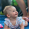 baby, smiling, pacifier, blue_quilt, floral_outfit, lying_down, happy, child, infant, cute, portrait, small_hands, soft_light, outdoor, blurred_background, skin, face, head, eyes, person