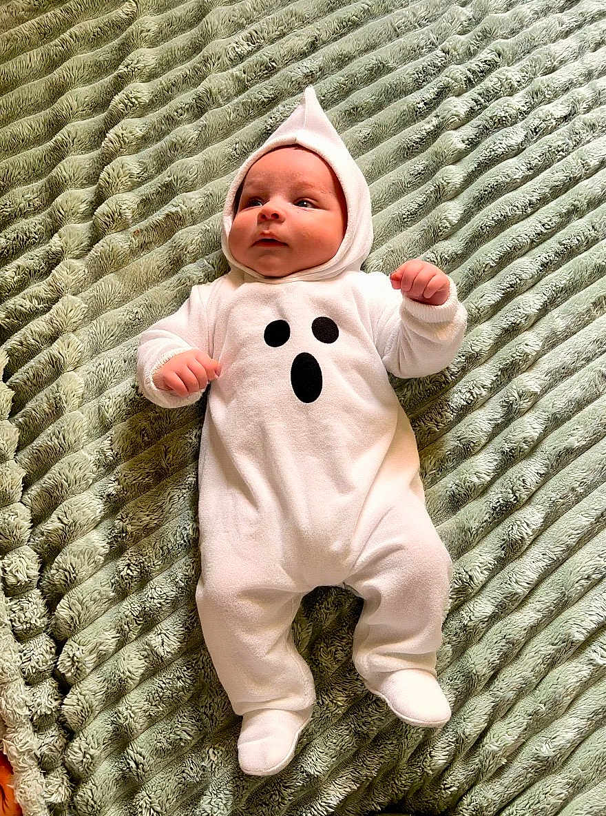 Zaiden joined the competition — help win amazing prizes! baby, infant, costume, ghost, onesie, hood, cute, lying_down, blanket, soft_texture, child, indoors, clothing, white, green, funny, expression, small_hands, comfortable, portrait