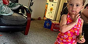 Raya is registered to the contest to win money with this photo: child, girl, living_room, carpet, clothing, shorts, tank_top, socks, furniture, chair, kitchen, refrigerator, lights, floor, toy, blanket, person, indoor, household, decor
