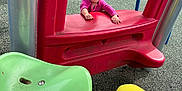 Zoey is registered to the contest to win money with this photo: toddler, child, playground, play_equipment, slide, red, green_seat, yellow_pants, outdoor, smiling, happy, grass, metal_poles, person, casual_clothing, daylight, recreation, fun, park, cute