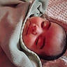 baby, blanket, bundled, close_up, eyes_closed, face, indoors, infant, mouth, newborn, nose, nursery, peaceful, photography, pink, portrait, resting, skin, sleeping, swaddled