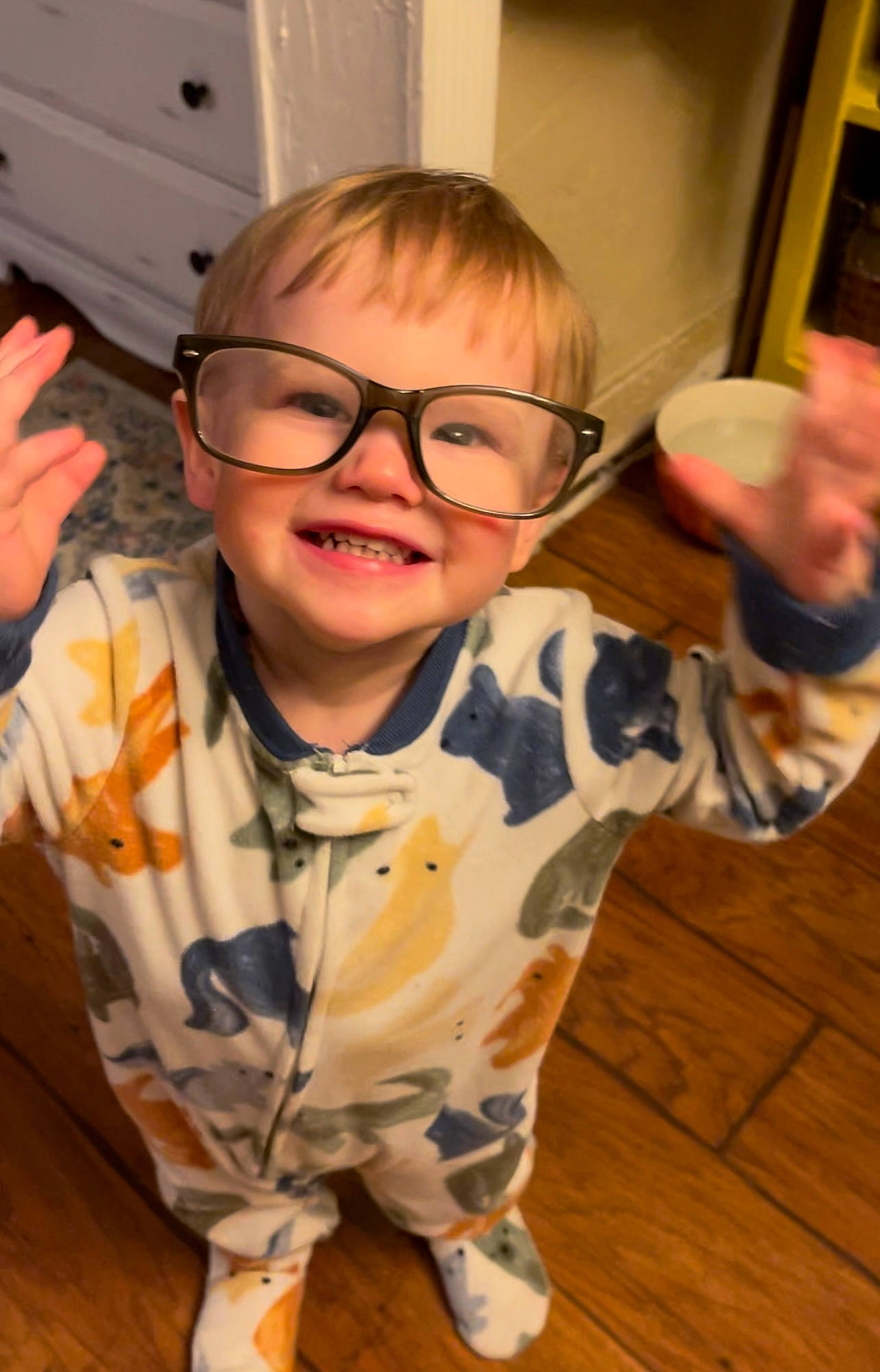 Truitt is registered to the contest to win money with this photo: arm, baby_toddler_clothing, child, eyewear, finger, flooring, fun, gesture, glasses, hand, happy, joint, joy, person, skin, sleeve, smile, standing, thumb, toddler