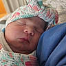 newborn, baby, sleeping, infant, portrait, close_up, swaddled, blanket, hat, floral, peaceful, cozy, face, eyes_closed, nose, mouth, skin, blue_clothing, indoor, candid