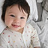 baby, bed, blanket, child, cozy, cute, face, happy, indoors, infant, onesie, polka_dots, portrait, resting, sleepwear, smiling, soft_lighting, toddler, tongue_out, young