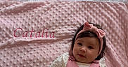 Catalia a rejoint le concours — aidez-le/la à gagner de superbes lots ! adorable, baby, bed_sheet, blanket, bow, cozy, dark_hair, embroidered_text, headband, infant, lying_down, pink_blanket, pink_outfit, plush_texture, portrait, ruffle_edge, small_hands, smiling, sunlight, white_shirt