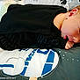 Alexander is registered to the contest to win money with this photo: baby, infant, black_clothing, blanket, pillow, lying_down, face, skin, newborn, child, sleepy, resting, cute, indoors, soft, patterned, closeup, comfort, small, peaceful