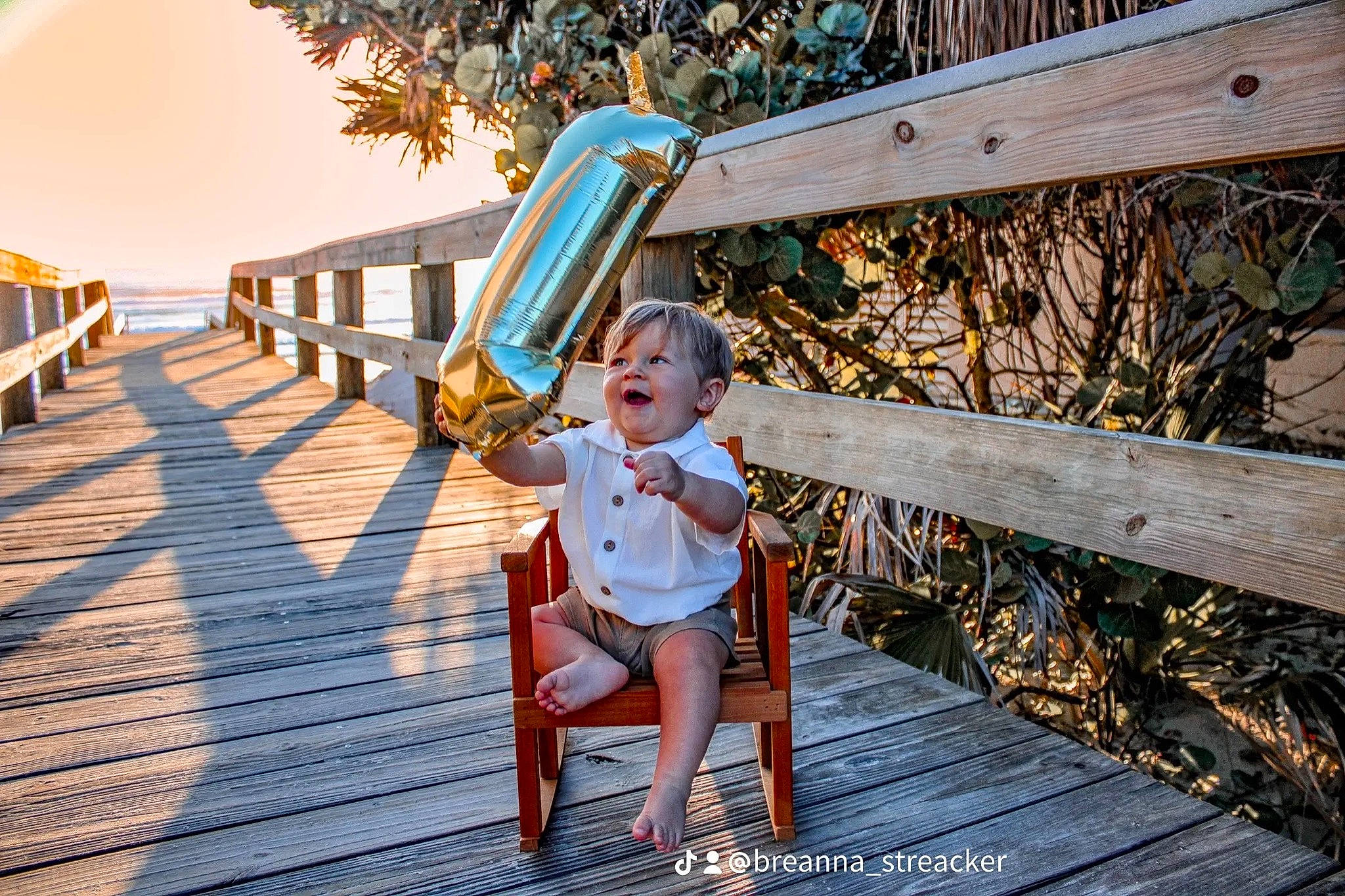Krew is registered to the contest to win money with this photo: baby, boardwalk, bridge, child, deck, fun, grass, happy, hat, landscape, leisure, people_in_nature, person, recreation, sitting, sky, sunlight, toddler, tree, walkway