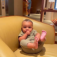 Royal is registered to the contest to win money with this photo: baby, child, thumb_sucking, chair, leather, indoor, person, foot, holding, relaxed, furniture, home, couch, seated, casual, infant, cute, portrait, skin, clothing