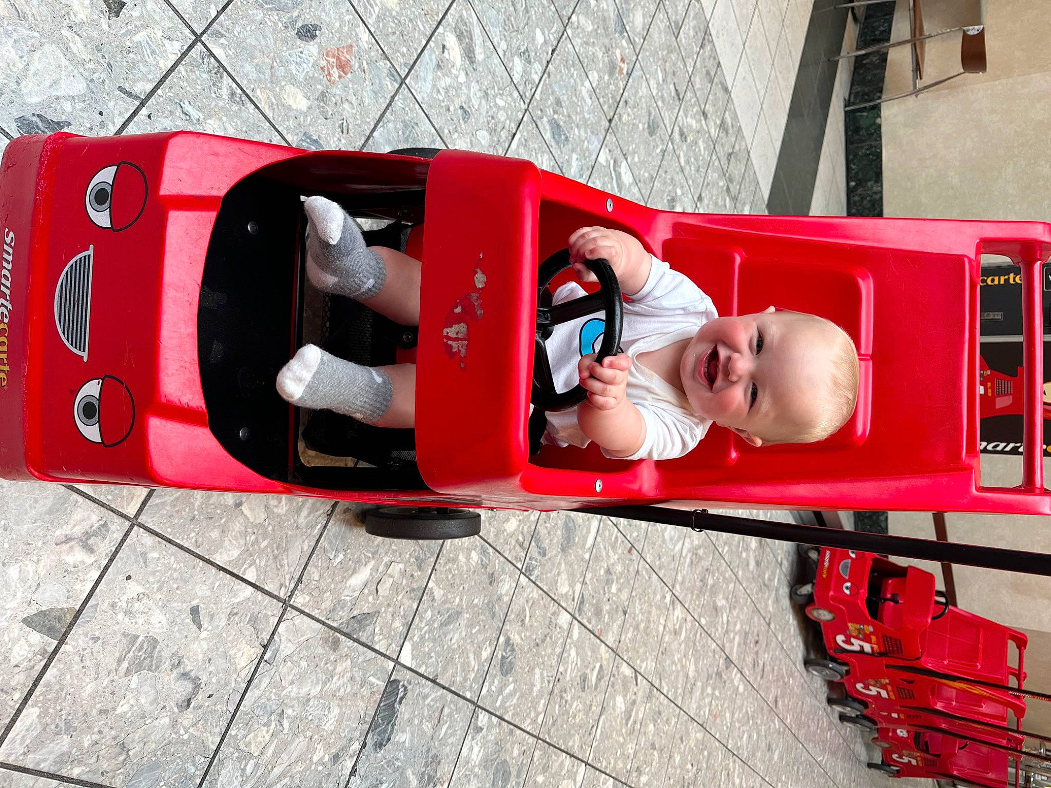 Kash is registered to the contest to win money with this photo: auto_part, automotive_design, automotive_exterior, automotive_lighting, automotive_wheel_system, bumper, carmine, joy, luxury_vehicle, machine, mode_of_transport, motor_vehicle, person, recreation, red, smile, tire, toddler, travel, vehicle