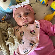 Ynaya participe au concours pour gagner de l'argent avec cette photo : baby, infant, headband, bib, pink_clothing, toy, plush_toy, playmat, face, child, cute, lying_down, indoor, colorful, comfort, soft_toy, pattern, mickey_mouse, expression, curious