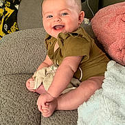 Frankie joined the competition — help win amazing prizes! baby, child, infant, smiling, happy, sitting, portrait, face, eyes, short_hair, onesie, clothing, bare_feet, blanket, pillow, couch, sofa, living_room, indoor, cozy
