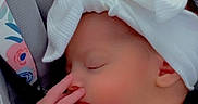 Frankie is registered to the contest to win money with this photo: baby, sleeping, infant, car_seat, bow, headband, white_clothing, portrait, face, closed_eyes, indoors, vehicle, seatbelt, blanket, hand, peaceful, lock_screen, smartphone_screenshot, notifications, close_up