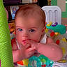 Frankie is registered to the contest to win money with this photo: baby, infant, child, portrait, sitting, play_seat, toy, teething, fingers, blue_eyes, brown_hair, indoor, playroom, colorful, baby_toys, activity_center, bottle, heart_overlay, happy, close_up