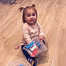 Lucia participe au concours pour gagner de l'argent avec cette photo : toddler, child, floor, wooden_floor, plastic_container, pigtails, sitting, indoor, curious, toy, clothing, socks, person, young_child, play, cute, expression, hair, flooring, container
