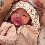 Taïsiana a rejoint le concours — aidez-le/la à gagner de superbes lots ! baby, infant, pacifier, pink_towel, floral_pattern, tattoo, hands, close_up, wrapped, cozy, sleepy, cute, newborn, soft_texture, blanket, person, face, skin, indoor, comfort