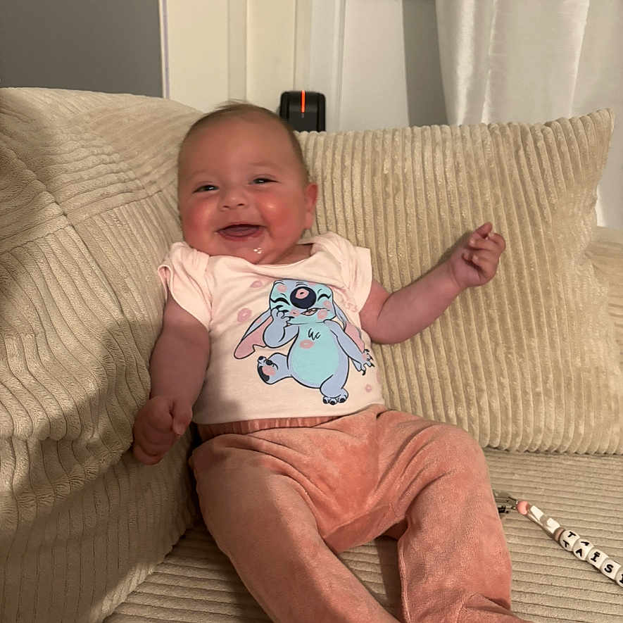 Taïsiana participe au concours pour gagner de l'argent avec cette photo : baby, cartoon_shirt, child, clothing, comfortable, corduroy, couch, cute, face, happy, home, indoor, infant, joyful, person, pillow, pink_pants, relaxed, sitting, smiling