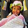 accessory, baby, blanket, car_seat, close_up, crocheted_blanket, crocheted_hat, cute, hands, happy, hat, indoor, infant, portrait, seat_harness, smile, smiling, tongue, toy, warm_lighting