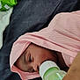 baby, bed, bedding, blanket, bottle, close_up, cozy, eye, fabric, face, feeding_bottle, hand, infant, mouth, nose, pink_cloth, portrait, resting, swaddle, tattoo
