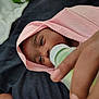 baby, baby_bottle, bed, bedding, blanket, caregiver_hand, close_up, cozy, eyes, face, feeding, hand, hood, indoor, infant, newborn, pink_cloth, portrait, skin, sleepy