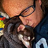animal, blanket, brown_fur, close_up, comfort, cozy, cuddling, dog, eyewear, face, fur, glasses, indoor, person, pet, portrait, resting, sleeping, snuggling, warm_clothing