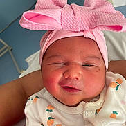 Carmen participe au concours pour gagner de l'argent avec cette photo : baby, newborn, infant, pink_headband, bow, onesie, fruit_pattern, sleepy, close_up, cute, child, portrait, person, soft_skin, adorable, clothing, wrapped, indoors, human, face