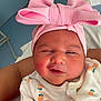 baby, newborn, infant, pink_headband, bow, onesie, fruit_pattern, sleepy, close_up, cute, child, portrait, person, soft_skin, adorable, clothing, wrapped, indoors, human, face