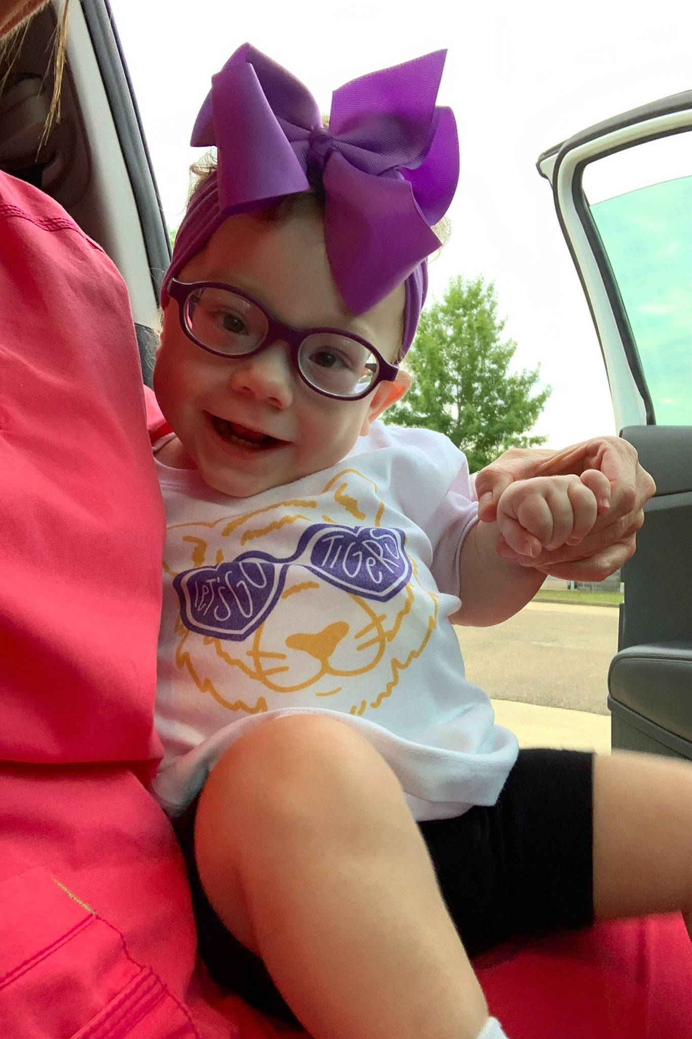 Kaisley joined the competition — help win amazing prizes! car_seat, child, costume_hat, event, eyewear, facial_expression, fun, happy, hat, human_leg, joy, lap, leisure, magenta, person, personal_protective_equipment, pink, recreation, sky, steering_wheel