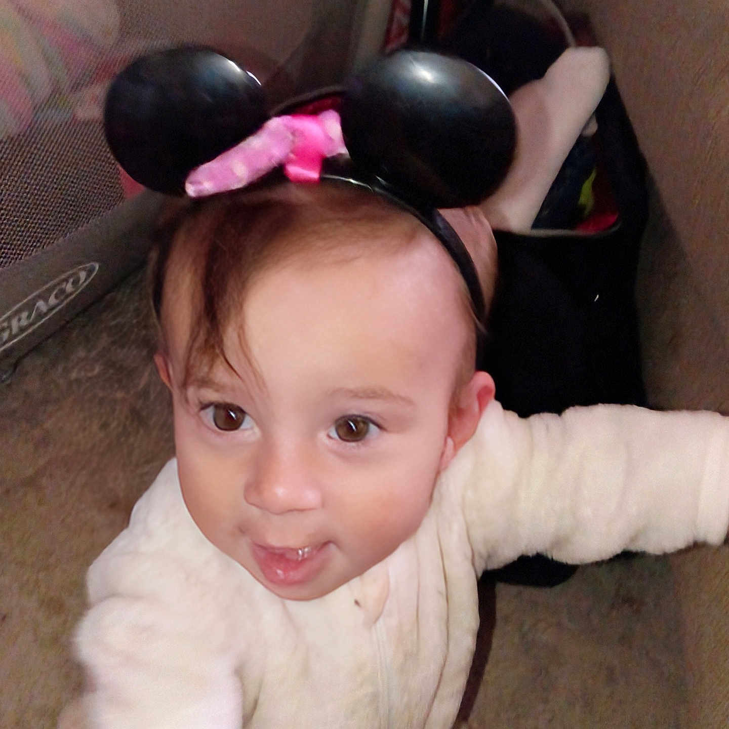 Jayda is registered to the contest to win money with this photo: baby, child, infant, portrait, face, eyes, smiling, happy, headband, mouse_ears, pink_bow, cream_clothing, long_sleeves, sitting, indoor, couch, furniture, carpet, closeup, playful