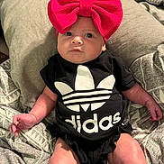 Kimberlyn joined the competition — help win amazing prizes! baby, infant, child, headband, bow, clothing, onesie, black_clothing, logo, adidas, bed, blanket, pillow, pattern, person, indoor, cute, face, skin, lying_down
