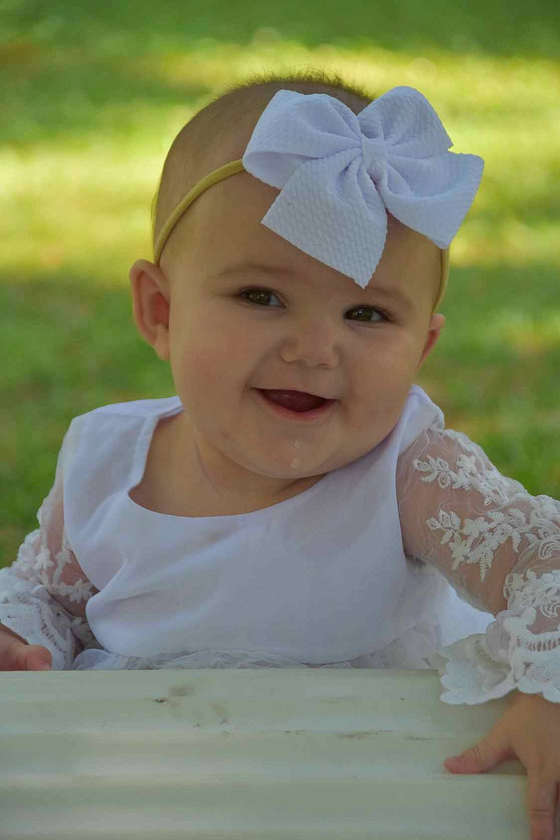 Gracelyn is registered to the contest to win money with this photo: baby, baby_toddler_clothing, cap, child, dress, eye, facial_expression, fun, grass, hair_accessory, happy, headgear, headwear, joy, leisure, person, pink, plant, product, skin