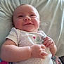 Isabelle is registered to the contest to win money with this photo: baby, smiling, infant, onesie, cactus, bed, blanket, happy, child, cute, skin, face, hand, lying_down, clothing, indoors, person, young_child, relaxed, soft_lighting