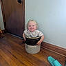 blue_slipper, casual, ceramic_crock, child, curly_hair, cute, door, doorknob, flooring, hands, home, indoor, light, plain_wall, playful, sitting, slipper, smiling, toddler, wooden_floor