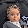 baby, child, blue_eyes, headband, stroller, blanket, clothing, face, person, infant, cute, portrait, young_child, straps, seat, closeup, outdoor, expression, skin, hair