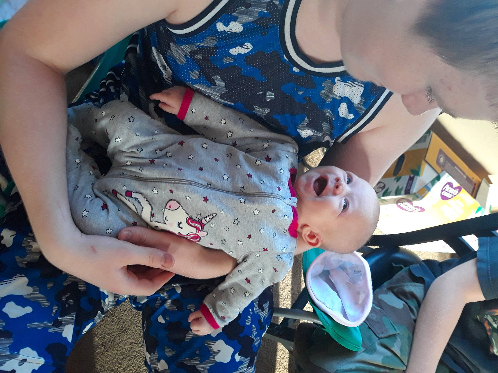 Kasey is registered to the contest to win money with this photo: arm, black_hair, blue, chest, child, cool, elbow, eyewear, fun, gesture, happy, human_leg, interaction, mouth, pattern, person, sitting, thigh, toddler, trunk