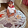 Haïlie Jeanne a rejoint le concours — aidez-le/la à gagner de superbes lots ! baby, glasses, red_bandana, milestone_blanket, floor, wooden_floor, smiling, sitting, indoors, white_shirt, decorative_blanket, orange_star, numbers, months, days, weeks, cute, child, portrait, happy