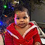 baby, child, red_robe, christmas_tree, christmas_lights, ornament, holiday, indoor, cute, smiling, face, person, festive, decorations, soft_lighting, blanket, cozy, warm, portrait, holiday_season